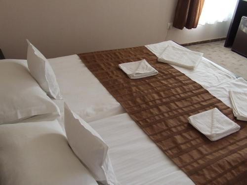 a large bed with white sheets and pillows on it at Pensiunea Caramell in Cluj-Napoca