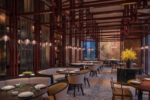 a rendering of a restaurant with tables and chairs at Conrad Shenzhen, the first art museum hotel in Greater Bay Area with the stunning bay and sunset view in the hotel terrace in Shenzhen