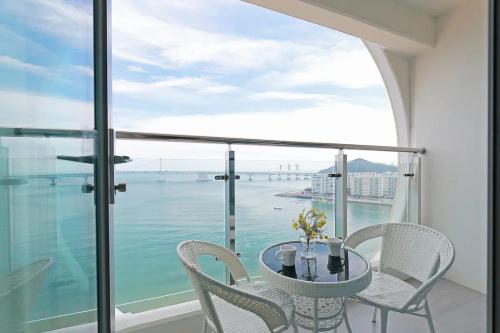 a table and chairs on a balcony with a view of the water at Elmomento Gwangan in Busan