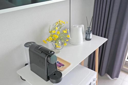 a white table with a tv and flowers on it at Elmomento Gwangan in Busan