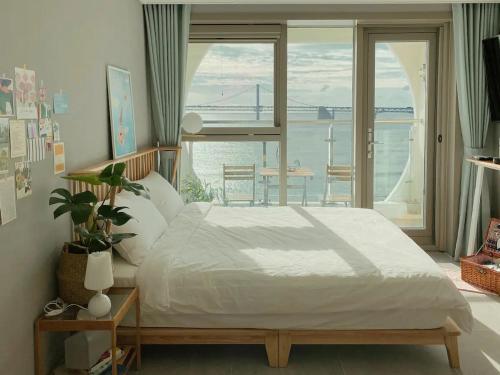 a bedroom with a bed and a view of the ocean at Elmomento Gwangan in Busan