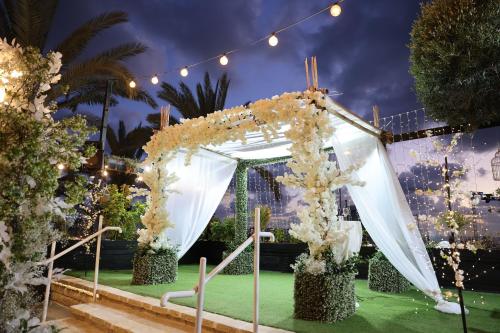 a wedding altar with white flowers and lights at Garden Hotel Boutique & Events in Haifa