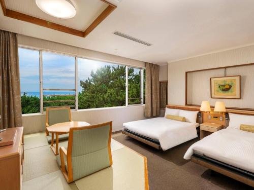 a hotel room with two beds and a large window at KAMENOI HOTEL Kamogawa in Kamogawa