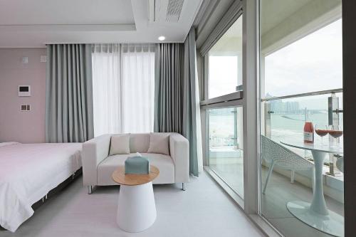 a bedroom with a bed and a chair and a table at Elmomento Gwangan in Busan
