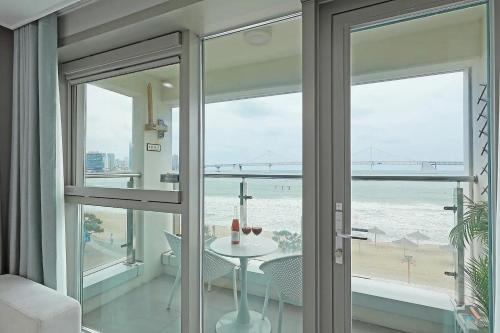 a room with a view of the ocean and a table at Elmomento Gwangan in Busan