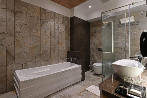 a bathroom with a tub and a sink and a toilet at Hotel Suba Star Ahmedabad in Ahmedabad