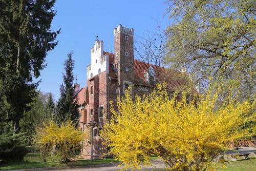 an old brick building with a tower on top of it at Zamek na wodzie w Wojnowicach in Wojnowice