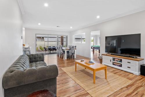 a living room with a couch and a tv and a table at Jakes Place in Dunsborough