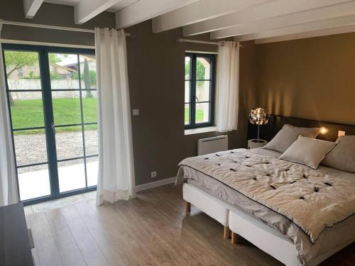 ein Schlafzimmer mit einem großen Bett und einem großen Fenster in der Unterkunft Demeure charentaise Standing - Grande Piscine - jacuzzi balnéo - Pool house in Barbezieux