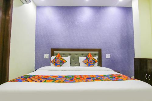 a bedroom with a large bed with a purple wall at FabExpress Kohinoor City in Chandīgarh