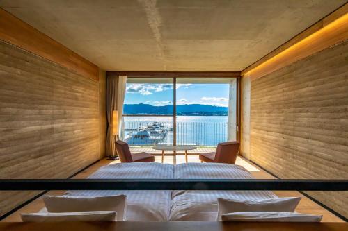 1 dormitorio con cama y vistas al agua en YANMAR SUNSET MARINA CLUBHOUSE&HOTEL, en Moriyama