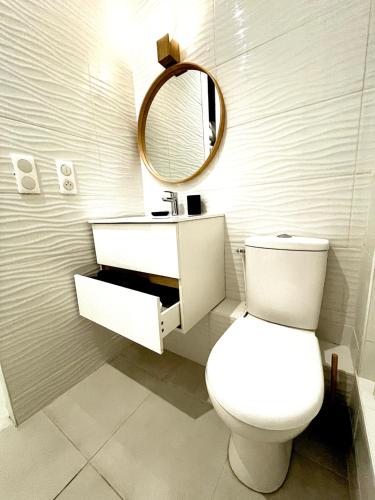 W łazience znajduje się biała toaleta i lustro. w obiekcie Très joli studio rue piétonne #3 w mieście Dreux