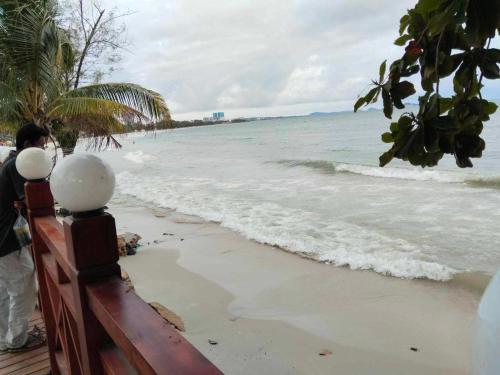 un hombre parado en la playa mirando el océano en Sea Inn Guesthouse Sihanoukville, en Sihanoukville
