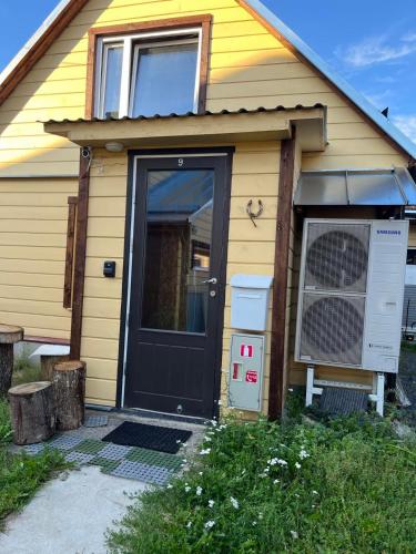 ein gelbes Haus mit einer schwarzen Tür und einem Ventilator in der Unterkunft Kodune Apartment Võru vanalinnas in Võru