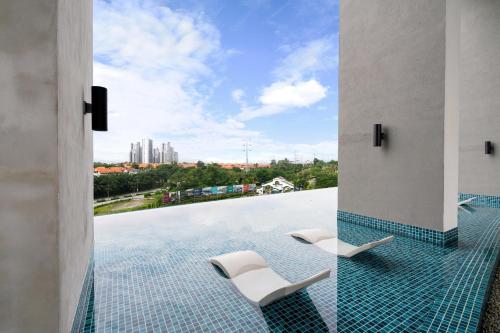 una piscina con 2 sillas y vistas a la ciudad en Modern & Minimalist 2-Bedroom Apartment in PJ en Petaling Jaya