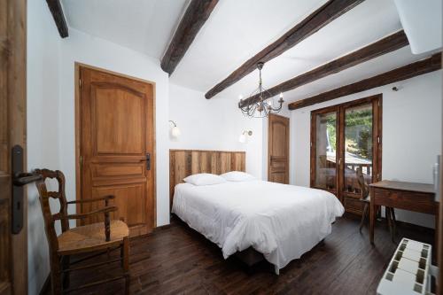 een slaapkamer met een wit bed, een bureau en een piano bij Chalet La Foux - Ancienne ferme rénovée in Allos