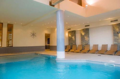 une grande piscine avec des chaises dans un bâtiment dans l'établissement Appartement les Coches-Monchavin, à La Plagne Tarentaise