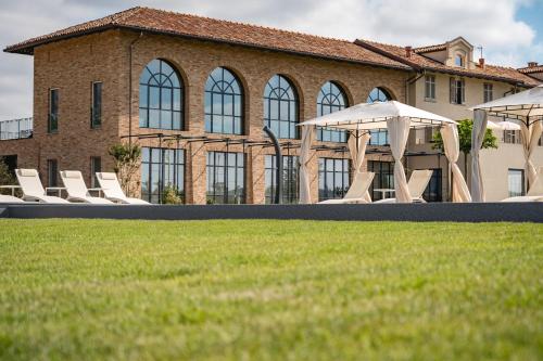 a group of lawn chairs and umbrellas in front of a building at Monvì Wine Relais in Costigliole dʼAsti