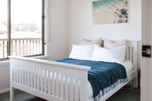 a bedroom with a white crib with a blue blanket at Omaru Beach House in Scamander