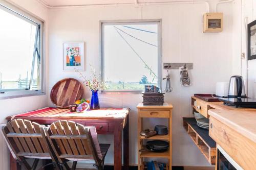 cocina con mesa, 2 sillas y ventana en FreeFall Hut, en Hastings