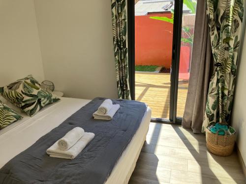 1 dormitorio con 1 cama con toallas en KazaCoco Bungalow à 5 min à pieds du lagon, en La Saline-Les-Bains
