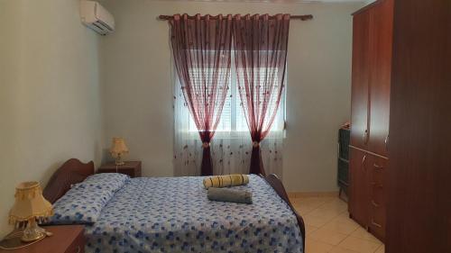 een slaapkamer met een bed en een raam met rode gordijnen bij Rent Apartament Bardho in Durrës