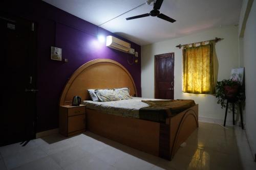 a bedroom with a large bed with a wooden headboard at Dmello Guest House in Canacona