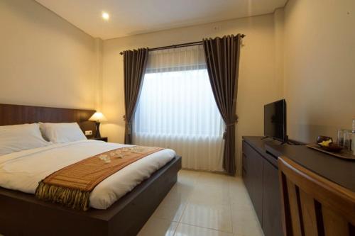 a bedroom with a bed and a tv and a window at Diva Lombok Resort in Senggigi 