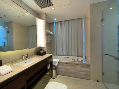 a bathroom with a sink and a tub and a mirror at The OCT Harbour, Shenzhen - Marriott Executive Apartments in Shenzhen