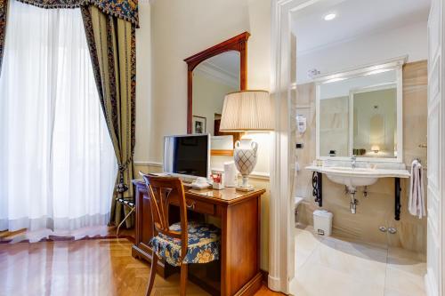 Habitación de hotel con escritorio, lavabo y espejo. en Hotel Cellini en Roma