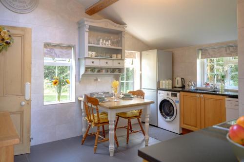 een keuken met een tafel en een wasmachine bij Saughall Mill Farm Cottage in Chester