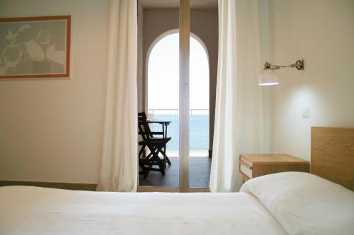 a bedroom with a bed and a door leading to a balcony at Mediterraneo Guesthouse in Giardini Naxos
