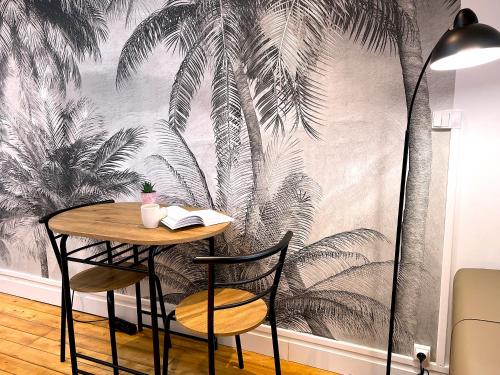 a table and chairs in front of a wall with palm trees mural at Studio de charme sous les toits #6 in Dreux