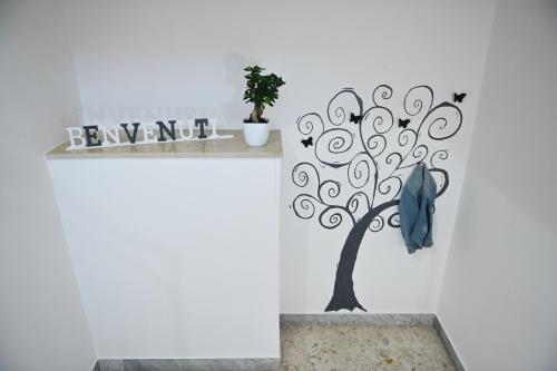 a tree wall sticker on a white wall with a blue jacket at casa Venezia in Carovigno