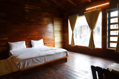 a bed in a wooden room with a window at Whispering Woods Chalet in Sasan Gir