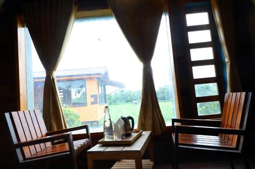a table and two chairs in front of a window at Whispering Woods Chalet in Sasan Gir