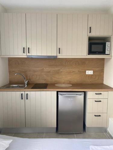 Una cocina con gabinetes blancos y un refrigerador de acero inoxidable. en Locanda Dei Sogni Originale, en Othonoí