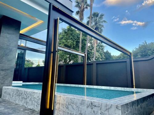 a swimming pool with two glass doors on a house at Futuristic Pool Villa with Stunning Mountain View in Chiang Mai