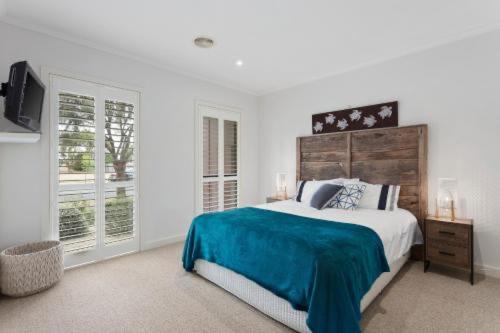 a white bedroom with a large bed and a television at Golf Beach Retreat Torquay in Torquay
