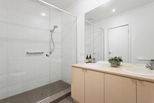 Golf Beach Retreat Torquay في توركوي: حمام أبيض مع دش ومغسلة