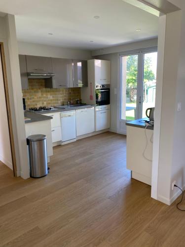 an empty kitchen with white appliances and wood floors at maison de vacances ninette in Névez
