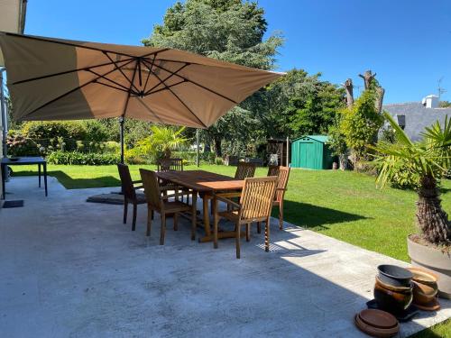 drewniany stół i krzesła pod parasolem w obiekcie maison de vacances ninette w mieście Névez