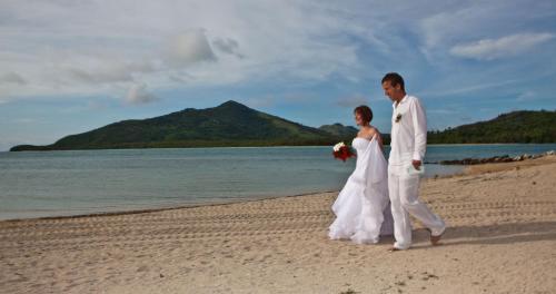 a bride and groom walking on the beach at Navutu Stars Resort in Matayalevu