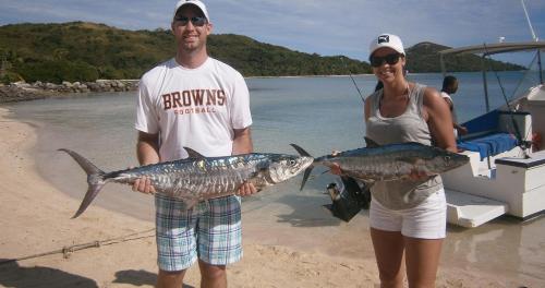 a man and a woman holding fish on a beach at Navutu Stars Resort in Matayalevu