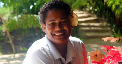 a woman with a flower in her hair standing next to flowers at Navutu Stars Resort in Matayalevu