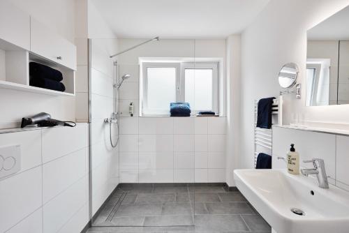 a white bathroom with a sink and a mirror at Apartmenthaus Emily by POLY Hohwacht in Hohwacht