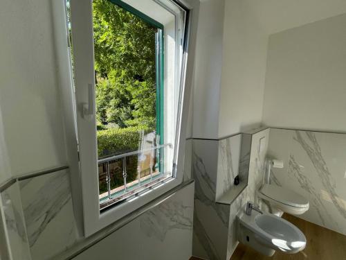 Novecento Luxury Residence 4 Stelle في Montese: حمام مع نافذة ومرحاض ومغسلة