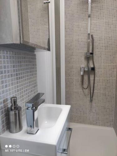 une salle de bain avec un lavabo blanc et une douche dans l'établissement Logement Stade de France/JO/7 minutes de Paris, à LʼÎle-Saint-Denis