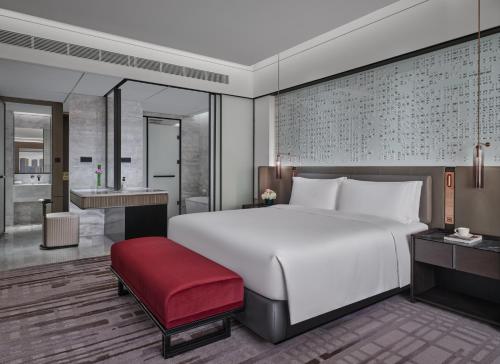 a bedroom with a large white bed and a red bench at InterContinental Shenzhen WECC by IHG in Shenzhen