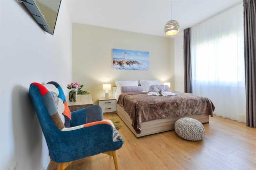 a bedroom with a bed and two blue chairs at 4* Villa First Hill with heated pool, Zaton in Zaton